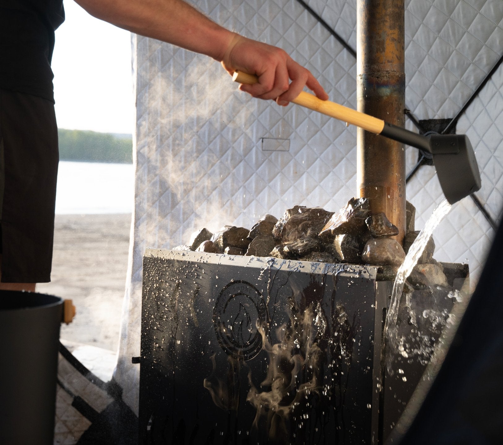 portable wood-burning sauna stove in use with water and steam